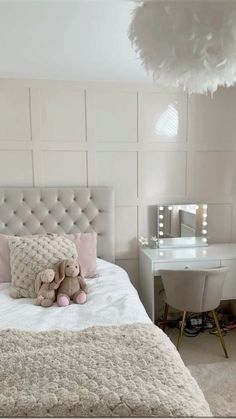 a teddy bear sitting on top of a bed next to a white desk and chair