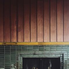 two towels are hanging on the fireplace in front of a tiled wall with wood paneling