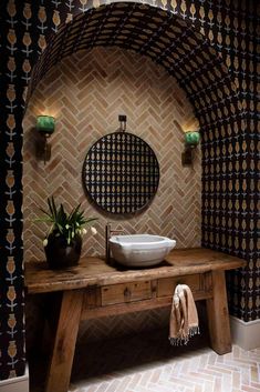 a wooden table topped with a white bowl under a mirror next to a wall mounted faucet