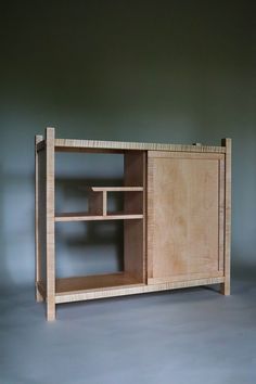 a wooden cabinet sitting on top of a gray floor next to a wall mounted shelf