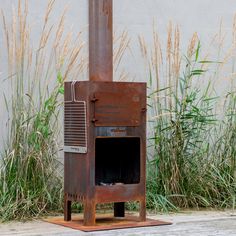 an old rusty stove sitting in front of some tall grass