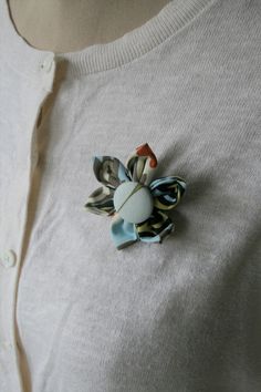 a woman wearing a white sweater with a flower brooch on it