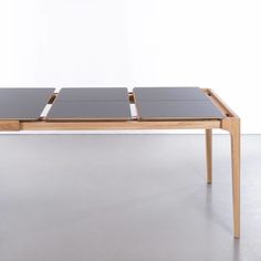 a wooden table with two black top and one brown bottom, on a gray floor