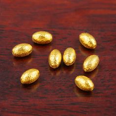 five gold eggs sitting on top of a wooden table