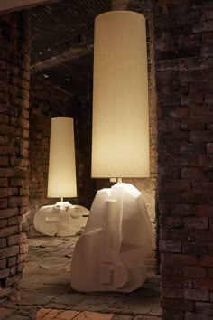 two lamps sitting on top of a brick floor next to a lamp in a room