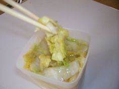 chopsticks sticking out of a container filled with food on a white counter top