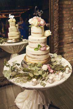 a wedding cake with flowers and greenery on a table