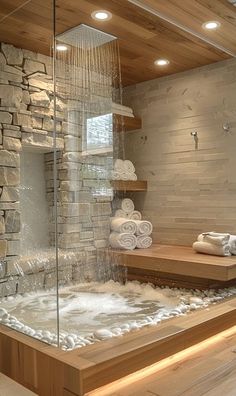 a bathroom with a stone wall and wooden flooring next to a large tub filled with water