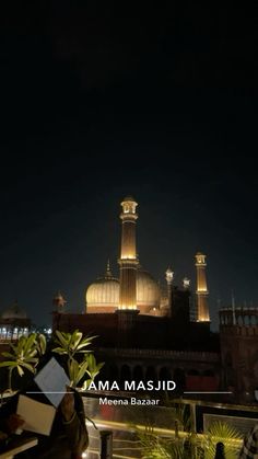 people are sitting outside at night in front of a large building with lights on it