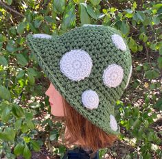 a woman wearing a green and white crocheted hat with polka dots on it