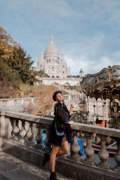 a woman standing on a bridge looking up at the sky and buildings in the background