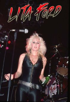 a woman in black leather outfit standing on stage