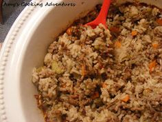 a white bowl filled with rice and meat on top of a table next to a red spoon