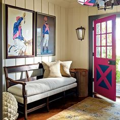 an entryway with a bench and two pictures on the wall above it, along with a red door