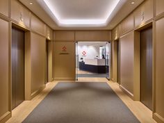 an empty hallway with wooden paneling and doors leading to the office building's reception area