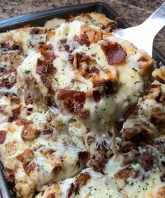 a close up of a pizza in a pan on a table with a spatula