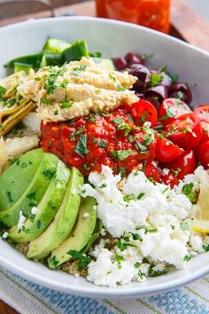 a bowl filled with rice, avocado, tomatoes and cucumber slices