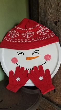 a white plate with a snowman face and red mittens on top of it