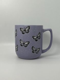 a purple coffee cup with black butterflies on the outside and white dots on the inside