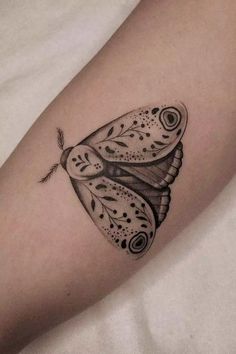 a black and white butterfly tattoo on the right arm, with an intricate design in it's wings