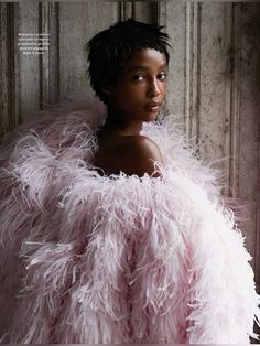 a woman with black hair wearing a pink feather coat