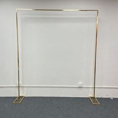 an empty room with a white wall and two gold metal poles on the floor,