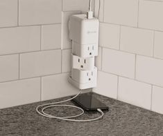 an electrical outlet plugged into a wall in a tiled room with white subway walls