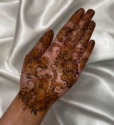 a woman's hand with hennap on it and white fabric in the background