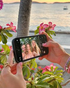 a woman taking a selfie with her cell phone in front of some pink flowers