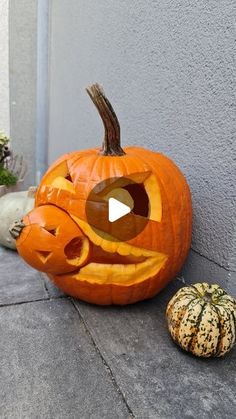 two carved pumpkins sitting on the ground next to each other, one with its mouth open