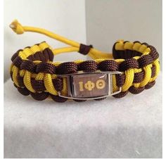 a yellow and brown rope bracelet with a square metal buckle on it's end