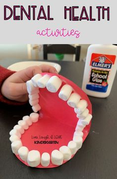 a child's hand holding a toothbrush over a plate with marshmallows on it