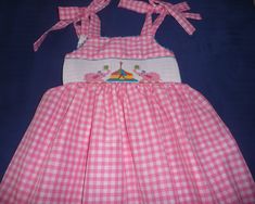 Hand smocked summer dress with pink elephants and circus. Ties at the shoulders and back. This could be a birthday dress. For other sizes allow 3 tweeks Playful Smocked Dress With Smocked Bodice For Summer, Playful Pink Dress With Smocked Back, Pink Smocked Dress For Playtime In Summer, Pink Smocked Dress For Summer Playtime, Playful Summer Smocked Dress, Playful Summer Smocked Dress With Smocked Back, Cute Pink Smocked Dress With Smocked Back, Playful Pink Dress With Smocked Bodice, Playful Pink Smocked Dress With Ruffles