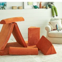 an orange sculpture sitting on top of a white floor next to a chair and ottoman