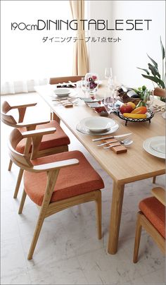 a dining table set with orange chairs and plates