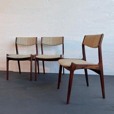 three chairs sitting next to each other in front of a white wall with no one on it