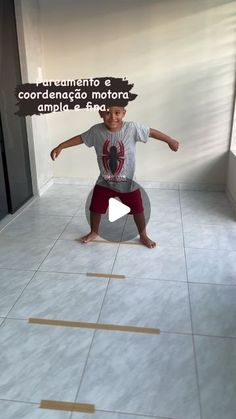 a young boy is standing on one leg in the middle of a room with tape taped to the floor