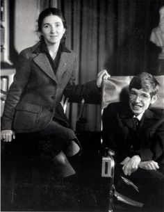 a man and woman sitting next to each other in front of a window with curtains