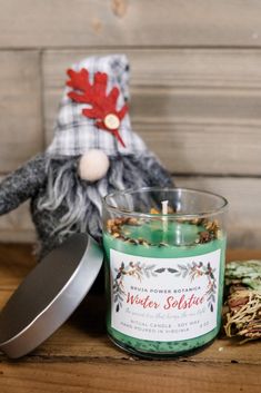 a green candle sitting on top of a wooden table next to a tin canister