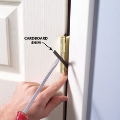 a person holding a pair of scissors in front of a door with the word card board on it