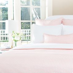 a bed with pink and white comforters in a bedroom next to a large window