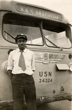 an old photo of a man standing in front of a bus