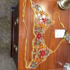 a wooden table topped with lots of colorful beads and chains next to a bottle opener