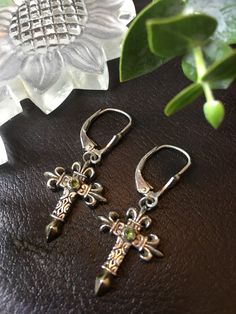 "Earrings ~, Cross Dangle Peridot Cabochon Artist Misti Martin Mystical Madness Cross Length: 7/8\" Cross Width: 5/8\" Sterling Silver Gold wash Cross Tips Peridot is associated with strength and balance, it is believed to bring peace, health, and rest - by harmonizing the mind and body. It is also thought to boost creativity and improve your mood. \"The inspiration for the jewelry comes from my fascination with the many natural resources that come from earth and sea. I consider jewelry making t Sterling Silver Cross Jewelry With Matching Earrings, Nickel-free Peridot Elegant Jewelry, Elegant Nickel-free Peridot Jewelry, Elegant Peridot Nickel-free Jewelry, Nickel-free Spiritual Jewelry For May Birthstone, Spiritual Green Gemstone Earrings, Nickel-free Silver Peridot Jewelry, Nickel-free Green Spiritual Jewelry, Green Nickel-free Spiritual Jewelry