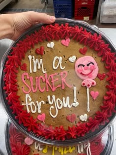 two cakes decorated with icing and decorations in the shape of hearts are being held by someone's hand