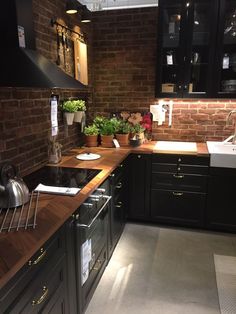 a kitchen with black cabinets and wooden counter tops, along with potted plants on the counters