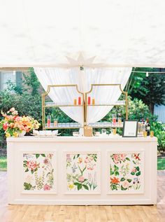 an outdoor bar with flowers painted on the front and sides, along with candles in vases