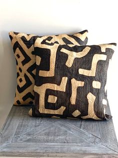 two black and white pillows sitting on top of a wooden bench next to a wall