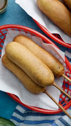 a hand holding a hot dog on a stick next to cucumbers and pickles