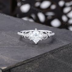 a white gold engagement ring with an intricate design on the side and diamonds in the middle